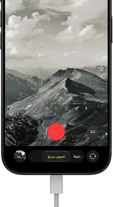 جهاز iPhone&nbsp;18&nbsp;Pro، الجهة الخارجية الأمامية، يعرض منظراً طبيعياً جبلياً، مع شريط نمط الكاميرا في نمط  التصوير السريع، وكابل طاقة موصول بمنفذ الشحن