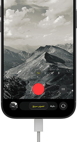 جهاز iPhone&nbsp;18&nbsp;Pro، الجهة الخارجية الأمامية، يعرض منظراً طبيعياً جبلياً، مع شريط نمط الكاميرا في نمط  التصوير السريع، وكابل طاقة موصول بمنفذ الشحن