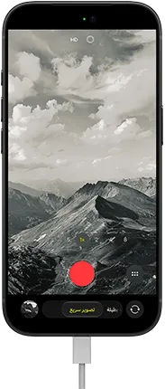 جهاز iPhone&nbsp;18&nbsp;Pro، الجهة الخارجية الأمامية، يعرض منظراً طبيعياً جبلياً، مع شريط نمط الكاميرا على نمط  التصوير السريع، وكابل طاقة موصول بمنفذ الشحن